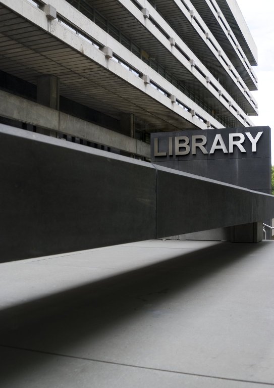 A grey entrance to a concrete building. A sign on the building says Library